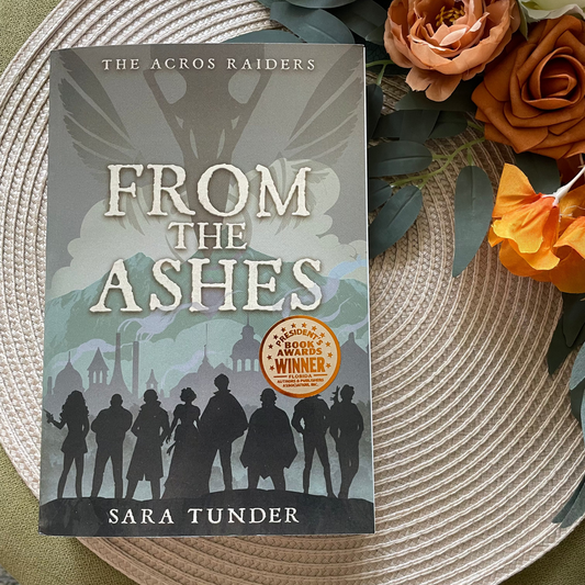 Book titled 'From the Ashes' by Sara Tunder on a woven mat with flowers